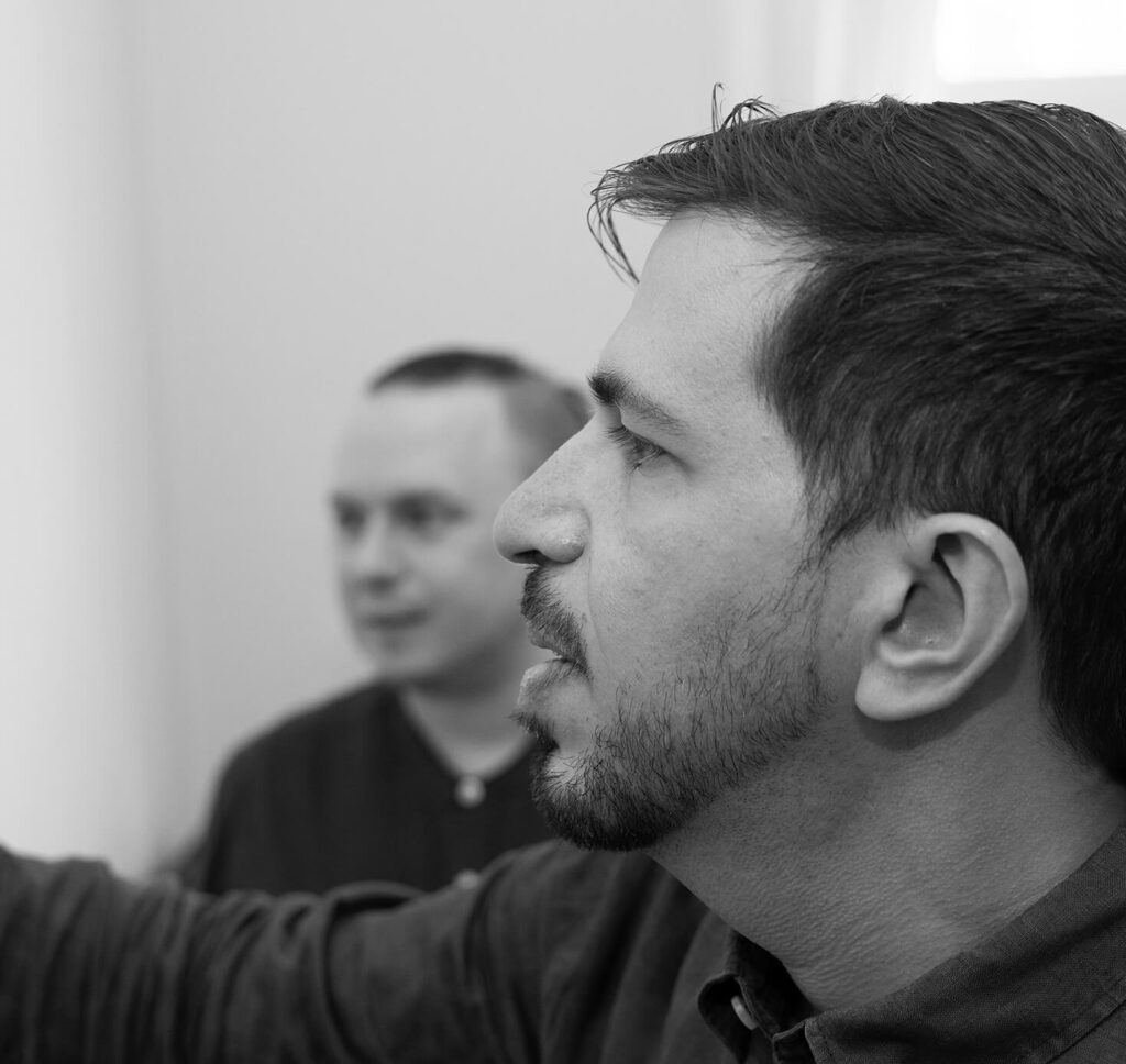 Gil writing on a whiteboard and Karl is watching